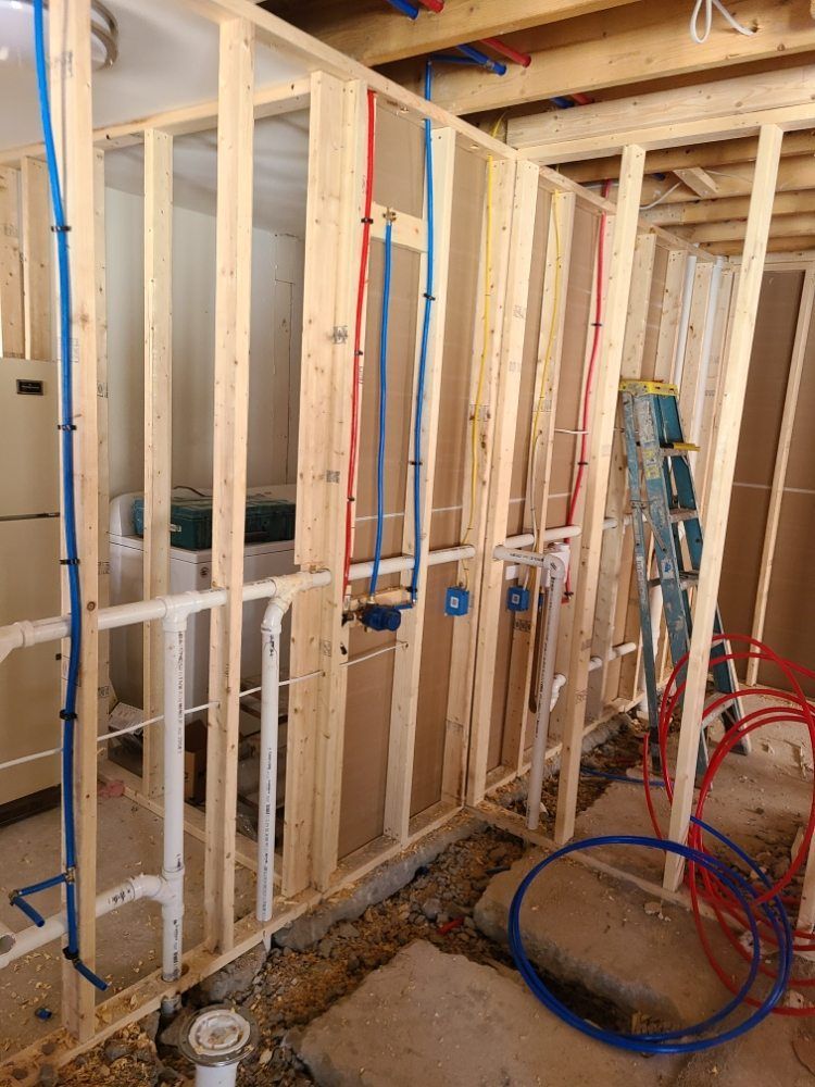 A room under construction with pipes hanging from the walls and a ladder.