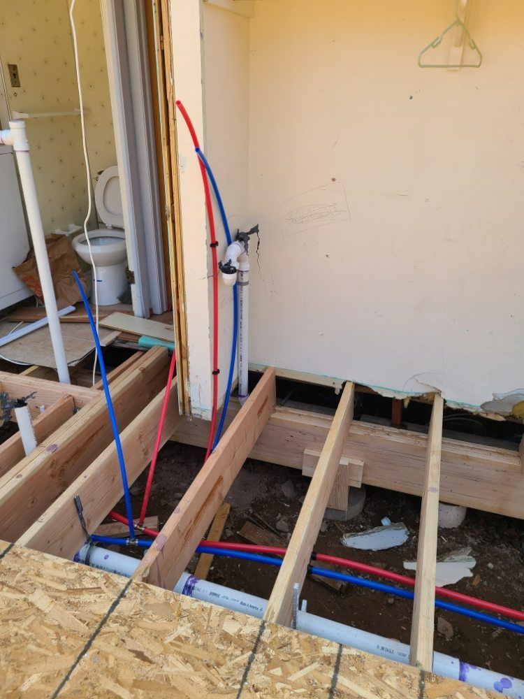 A bathroom under construction with red and blue pipes