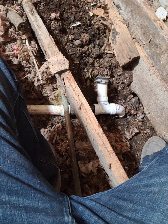 A person is working on a pipe in the dirt.