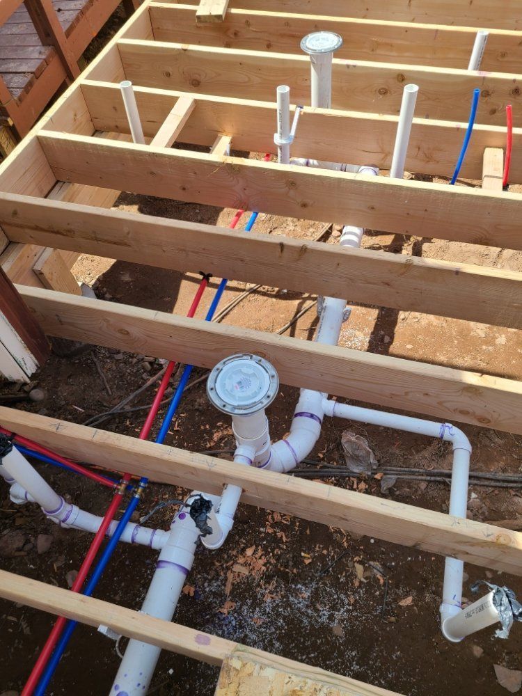 A bunch of pipes are under a wooden floor