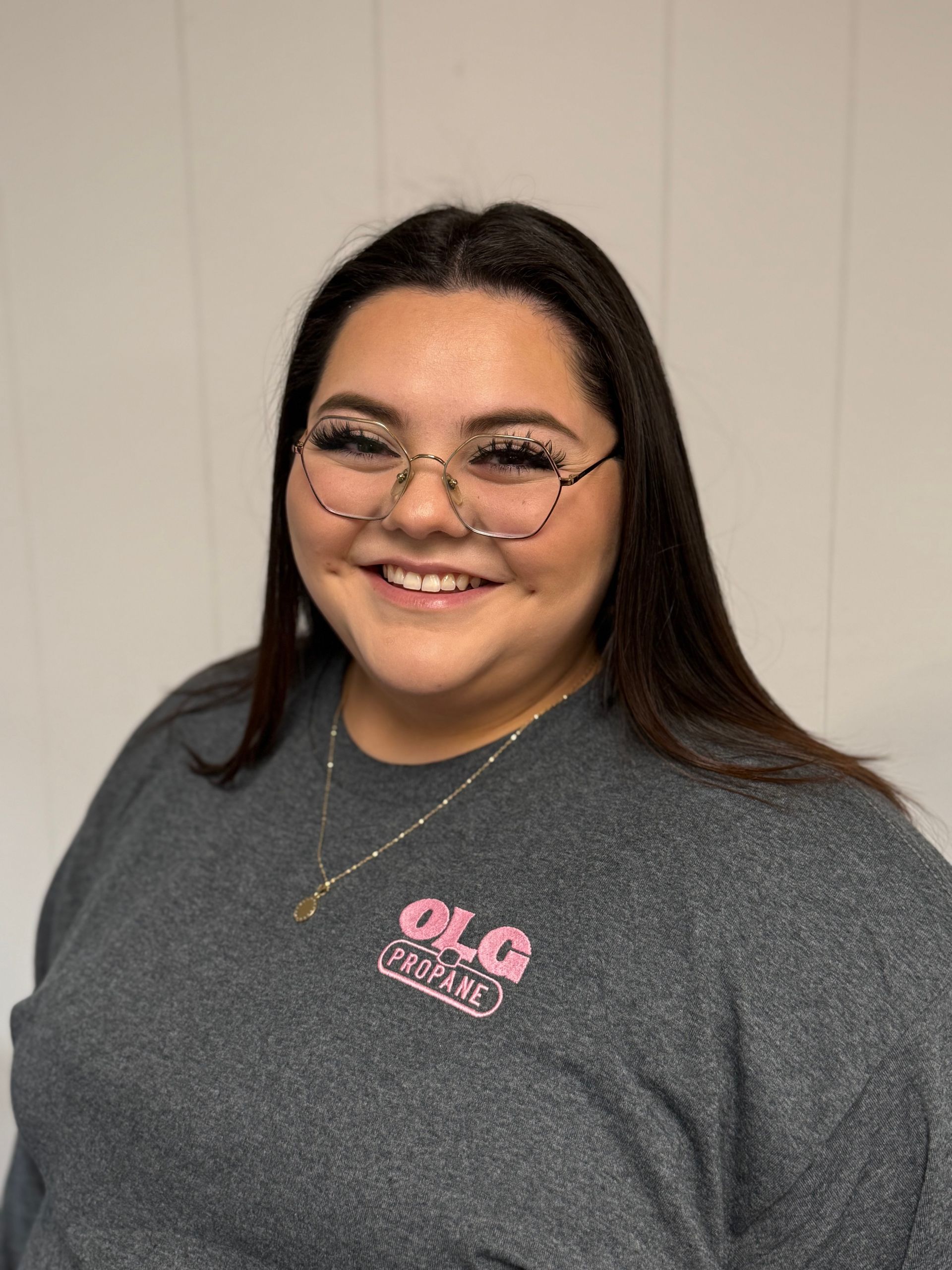 Person smiling, wearing glasses and a gray sweatshirt with