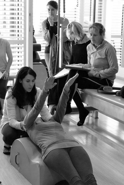 A woman is doing exercises on a pilates machine in a black and white photo.