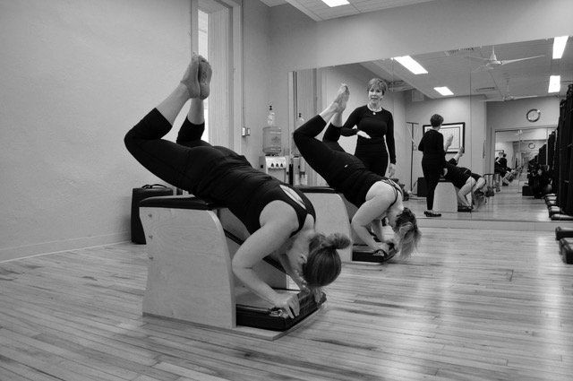 A black and white photo of two women doing pilates