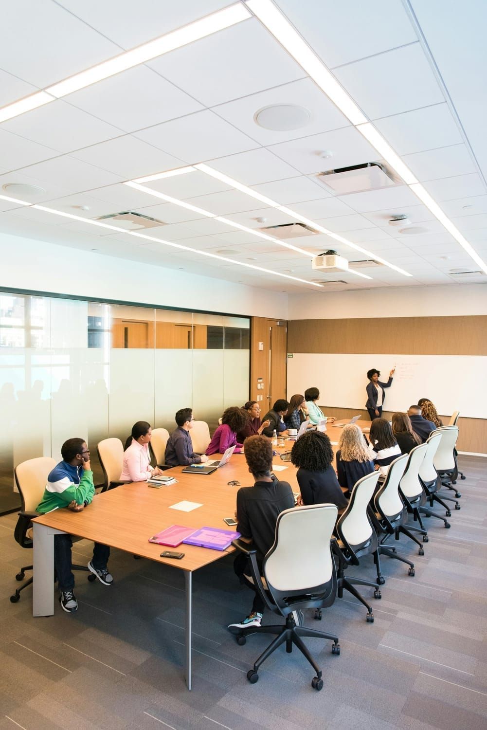 A group of people are sitting at a long table in a conference room.