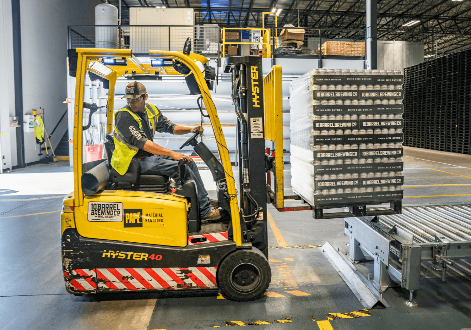 A man is driving a forklift in a warehouse.