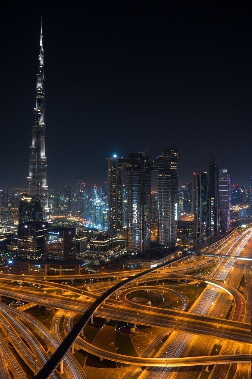 An aerial view of a city at night with a very tall building in the background.
