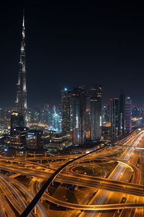 An aerial view of a city at night with a very tall building in the background.