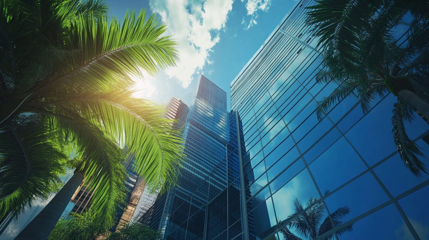 Looking up at a city skyline with palm trees and the sun shining through the windows.