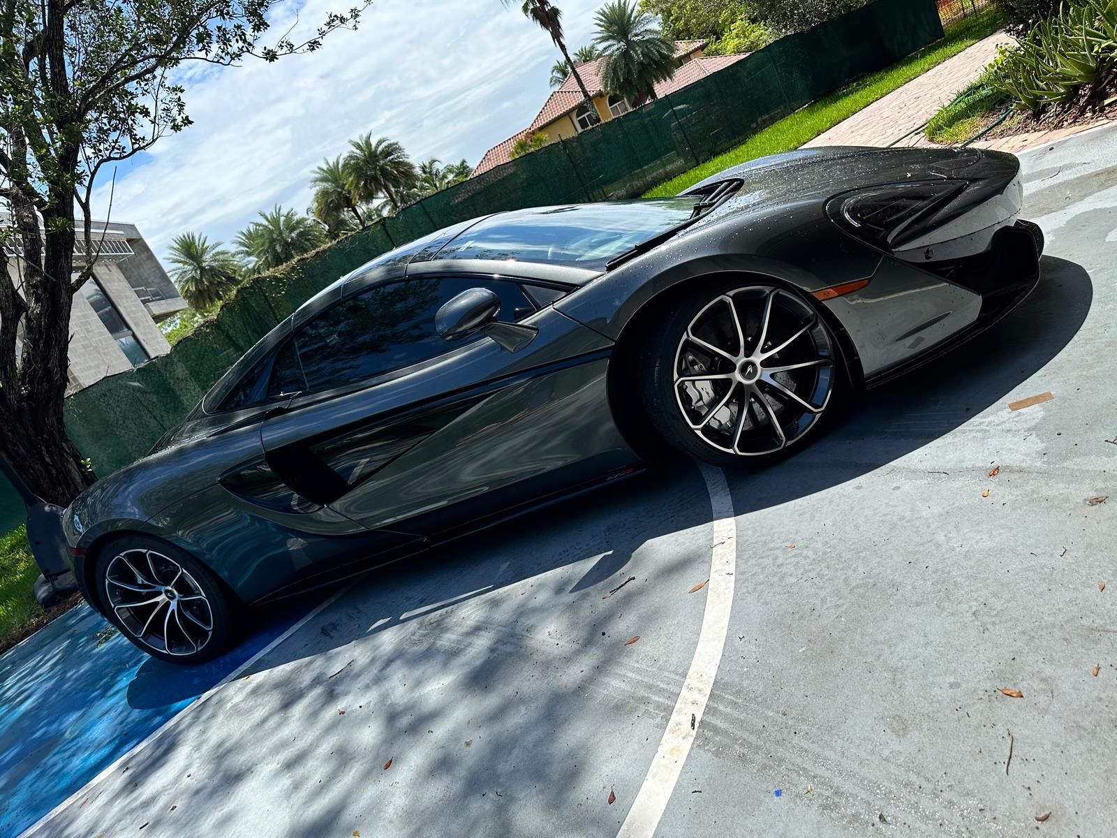 A gray sports car is parked on the side of a road.