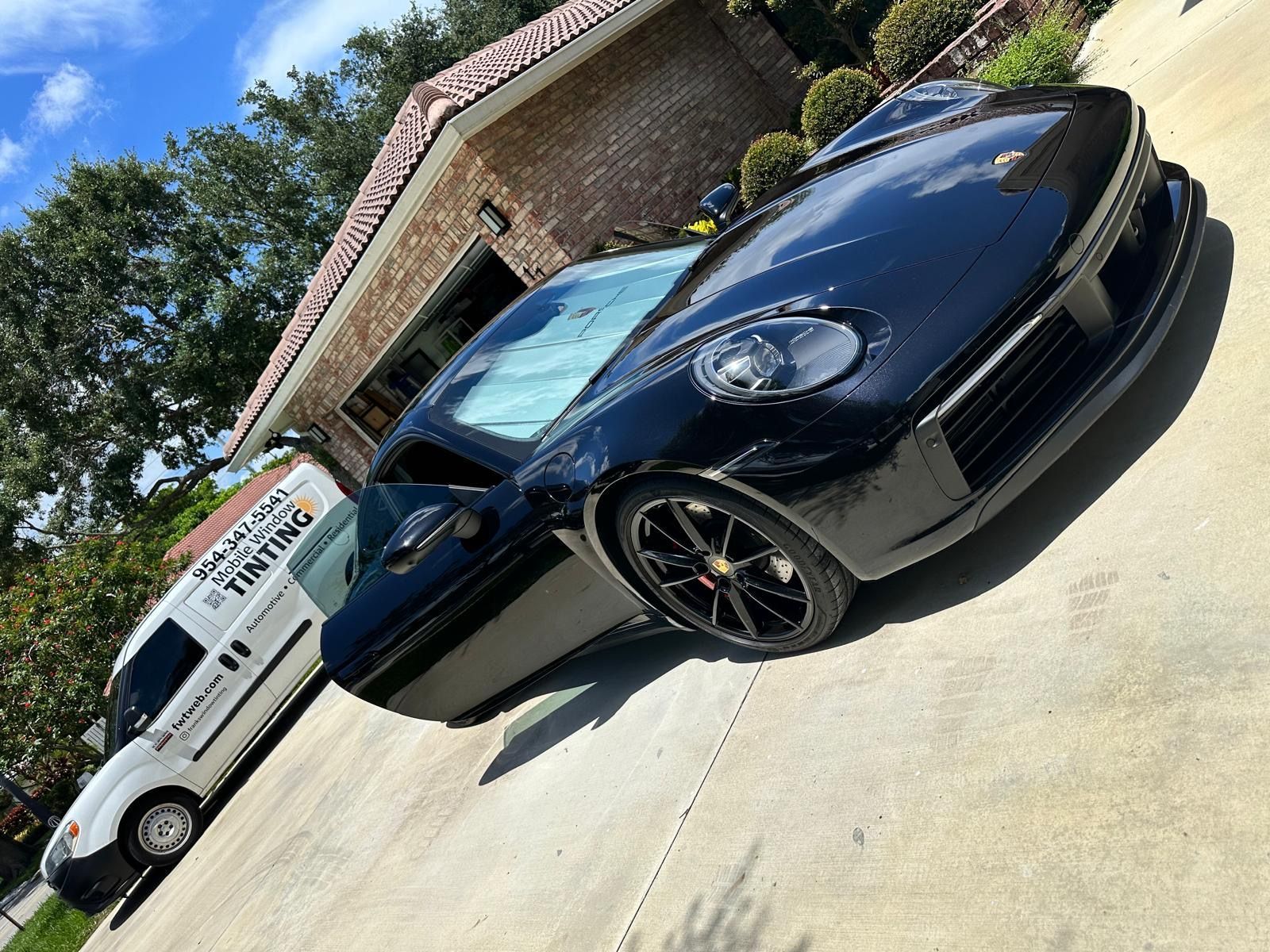 A black sports car is parked in front of a house.
