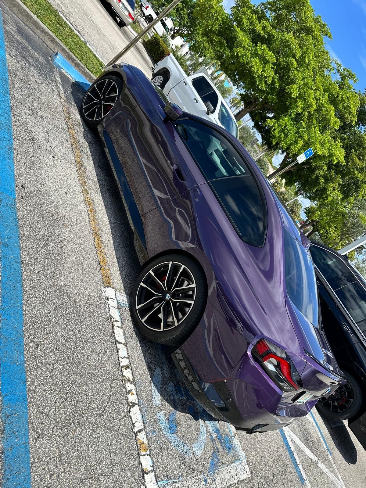A purple car is parked in a handicapped parking spot.