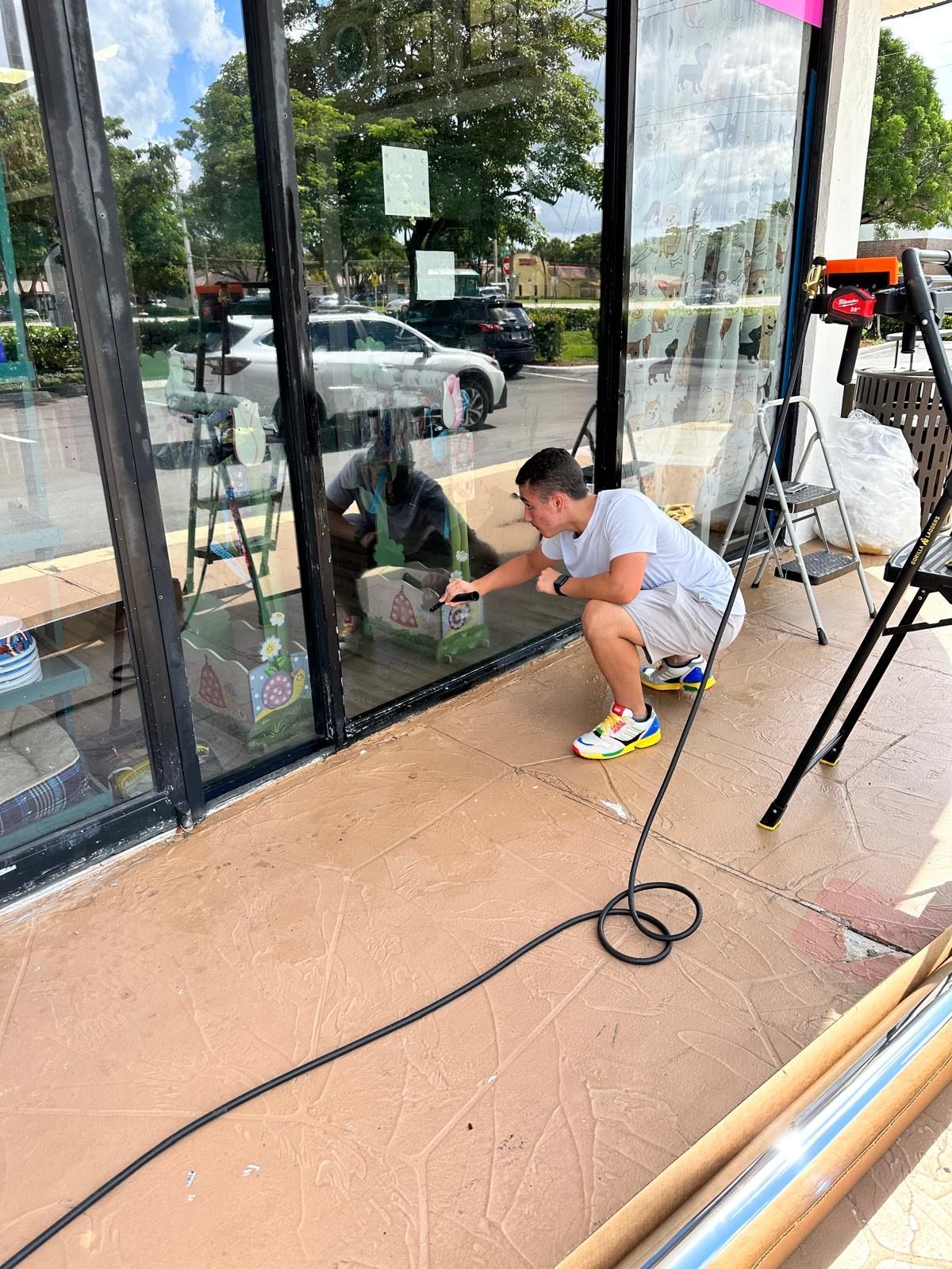 A man is kneeling down in front of a store window.