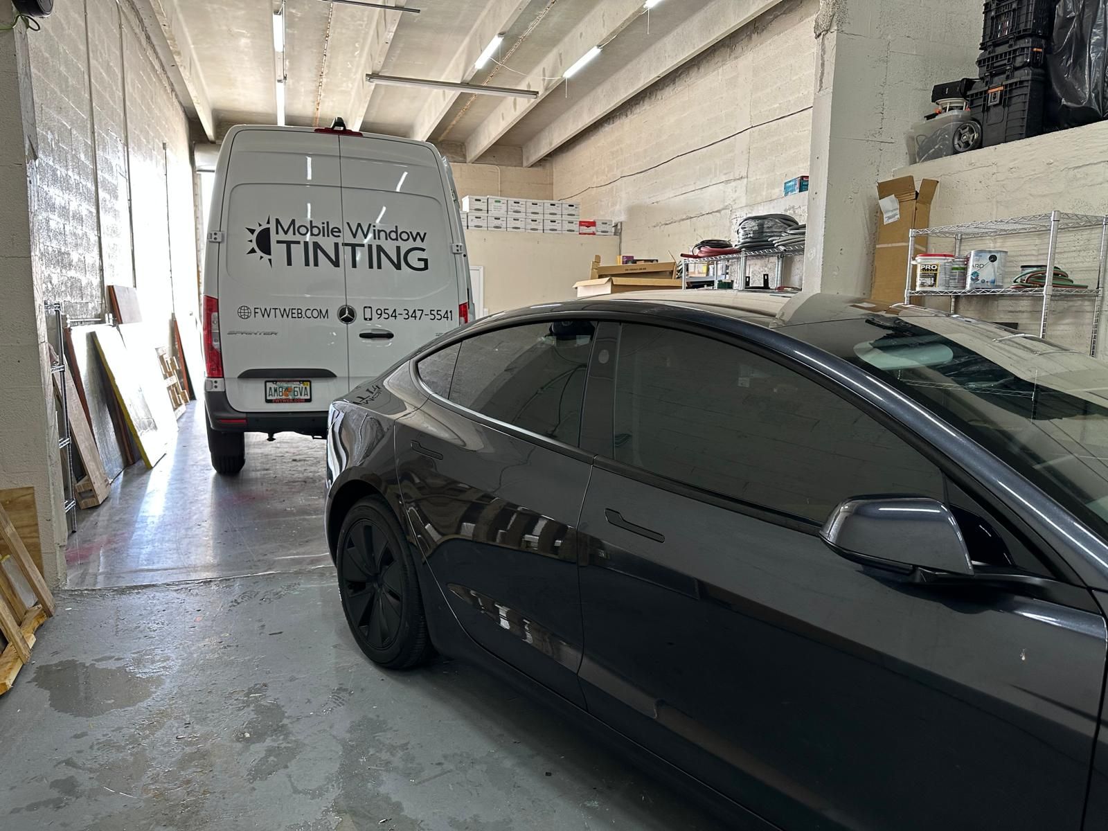 A car is parked next to a van in a garage.