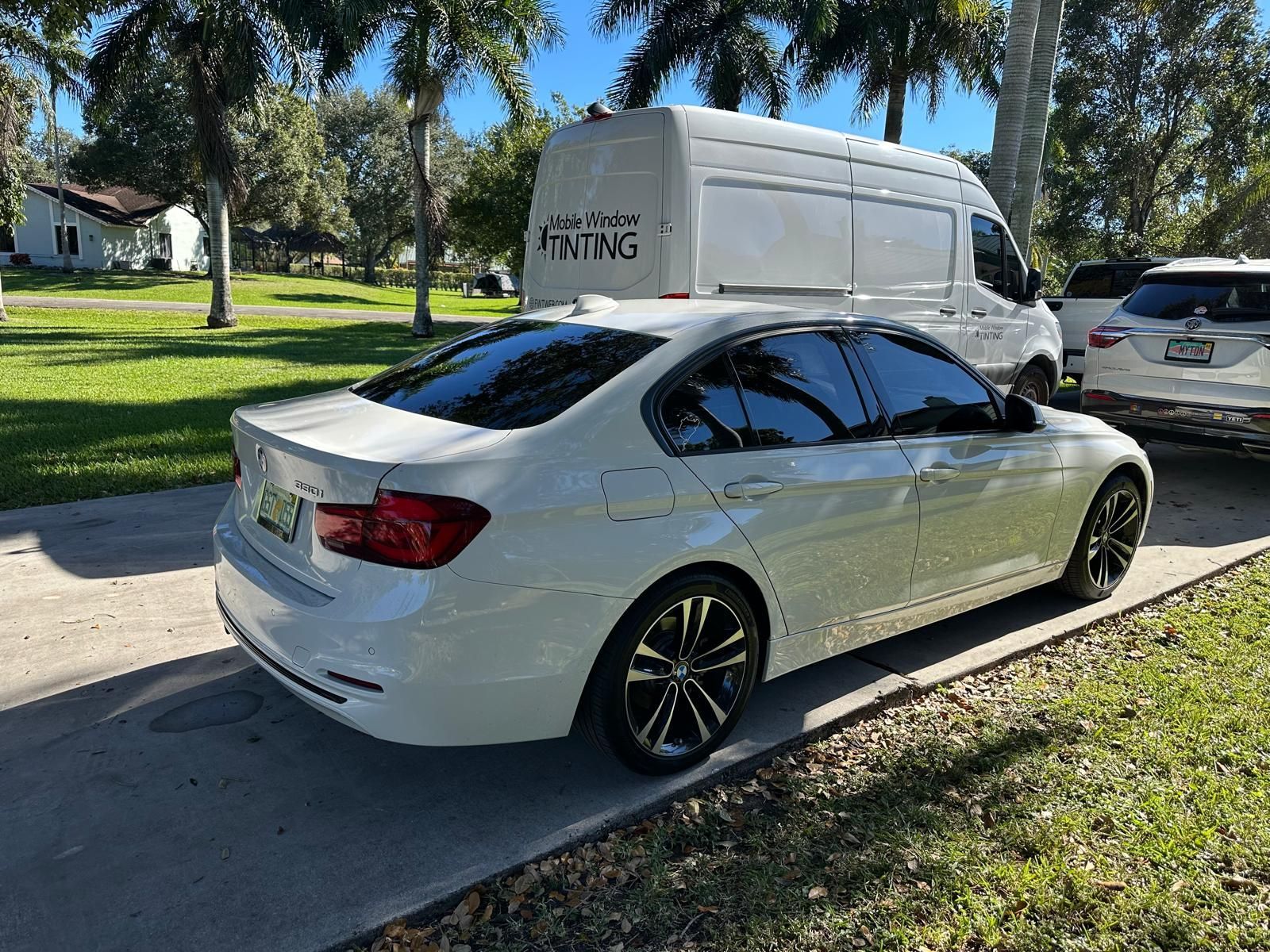 A white car is parked next to a white van.