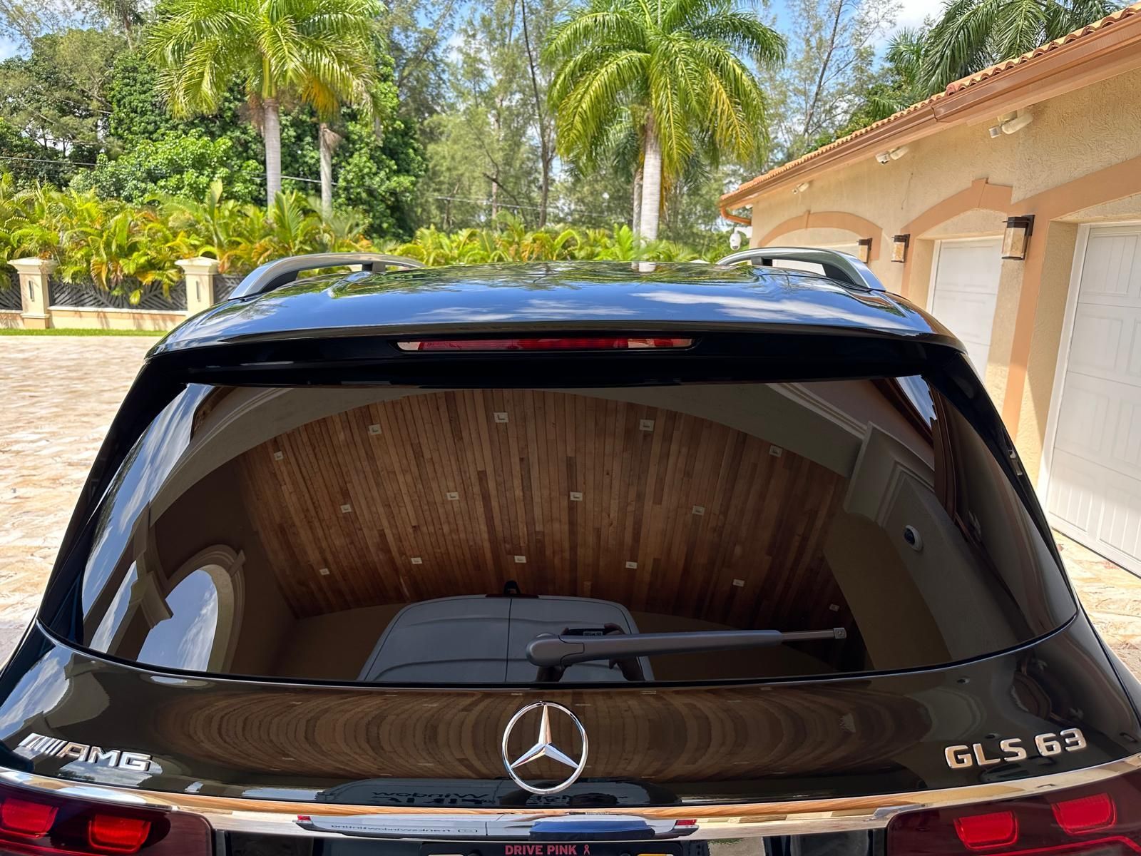 A black mercedes benz gls 63 is parked in front of a garage.