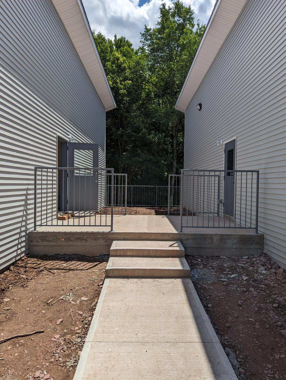 A concrete walkway between two buildings with a metal railing.