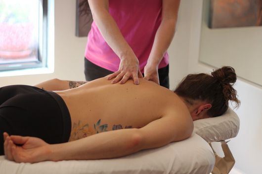 A woman is giving a man a massage on a table.