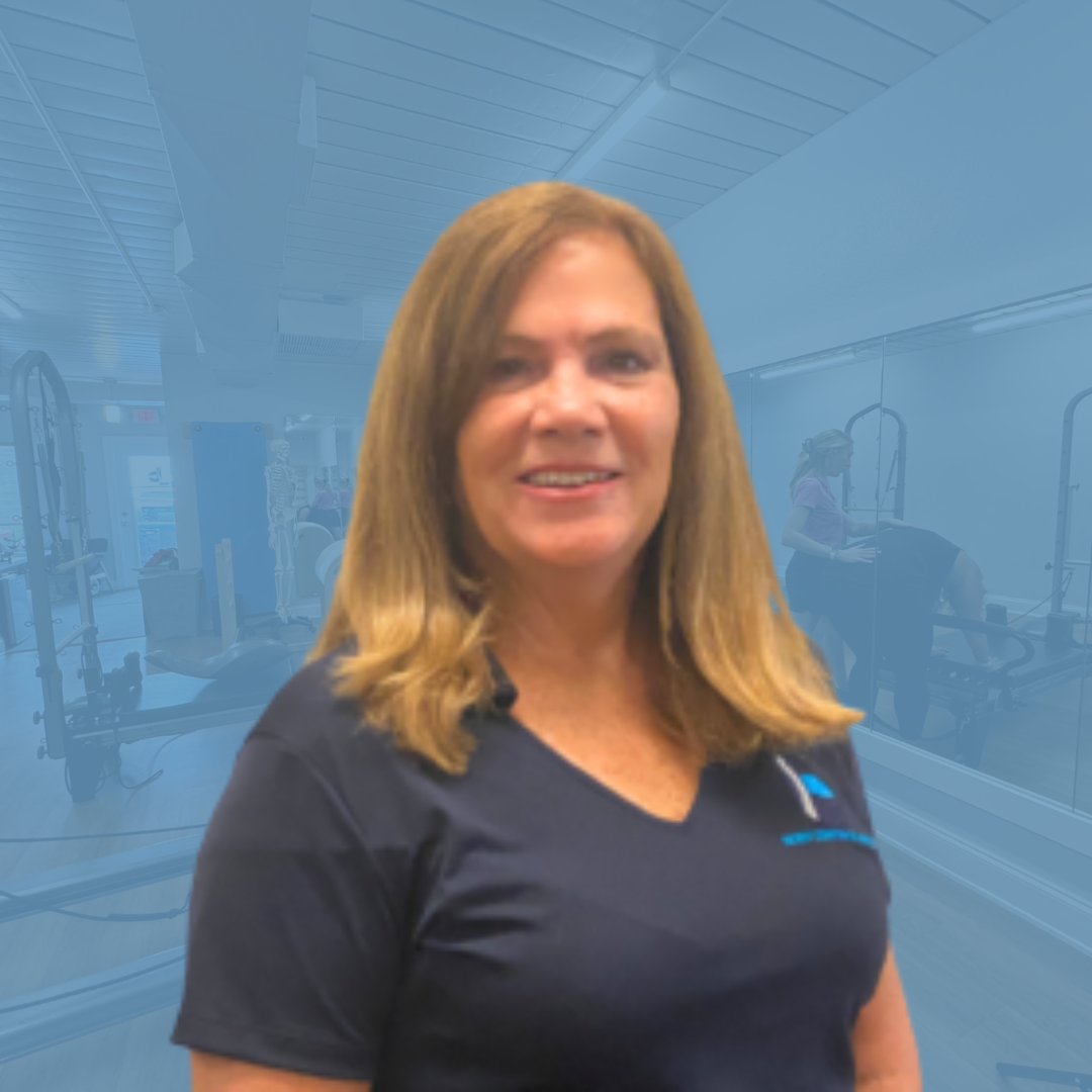 A woman in a blue shirt is smiling in front of a blue background.