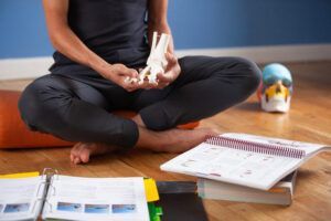 A person is sitting on the floor holding a model of a foot.