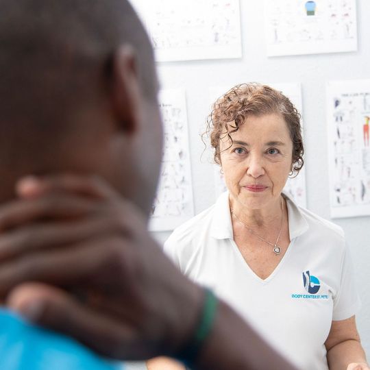 A woman in a white shirt is talking to a man in a blue shirt.