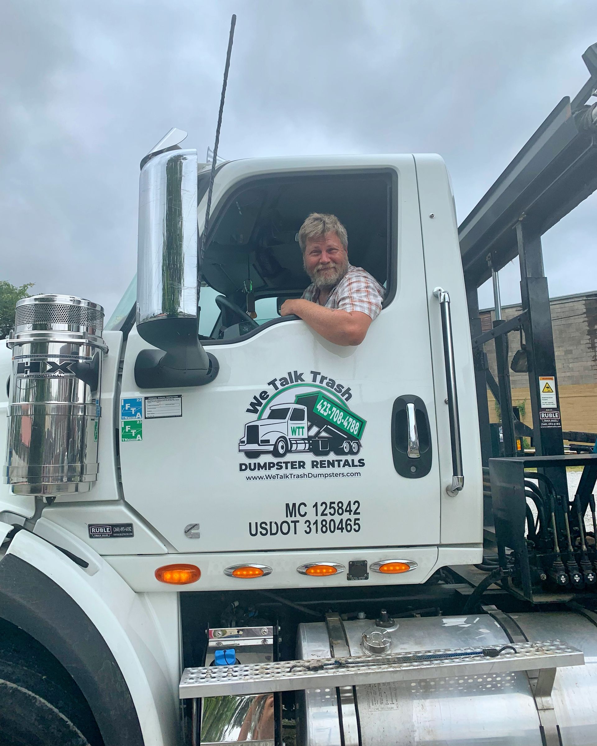 A man is sitting in the driver 's seat of a white truck.