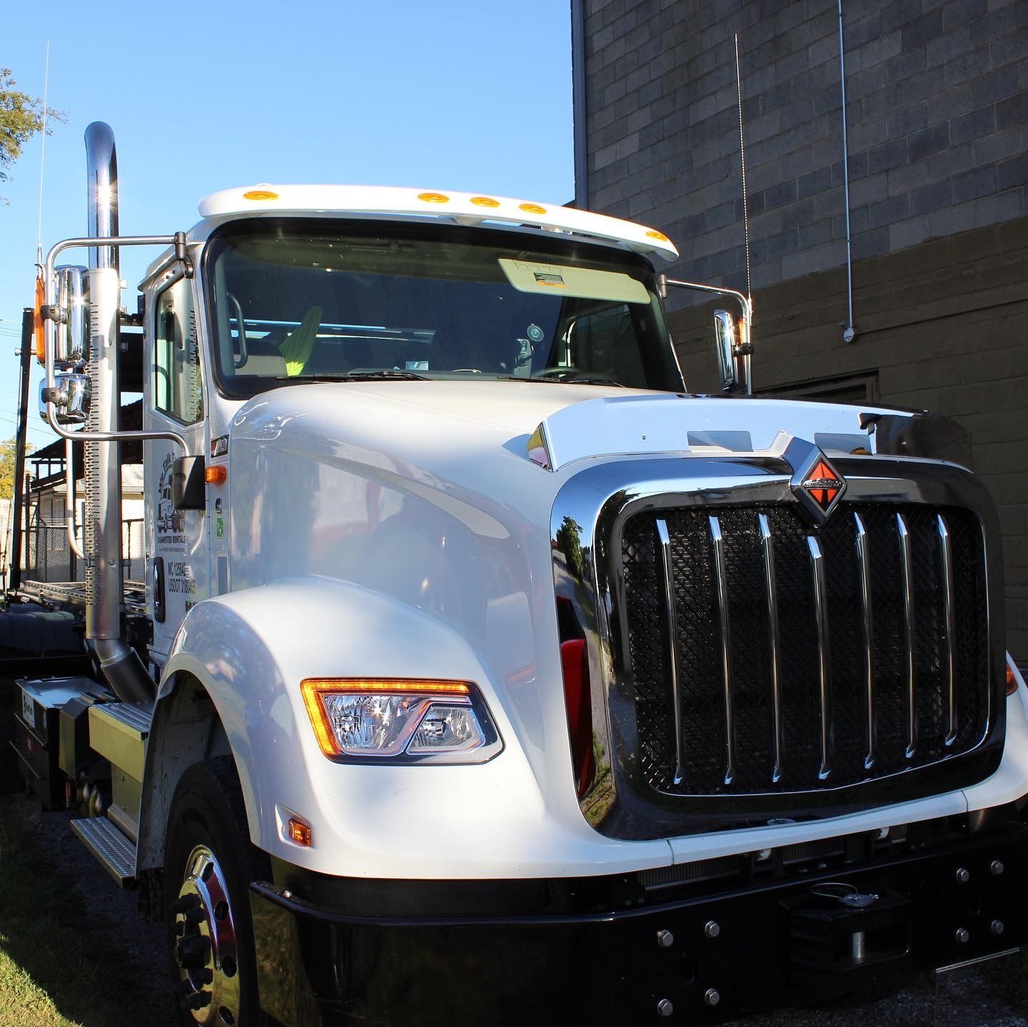 A white semi truck is parked in front of a brick building