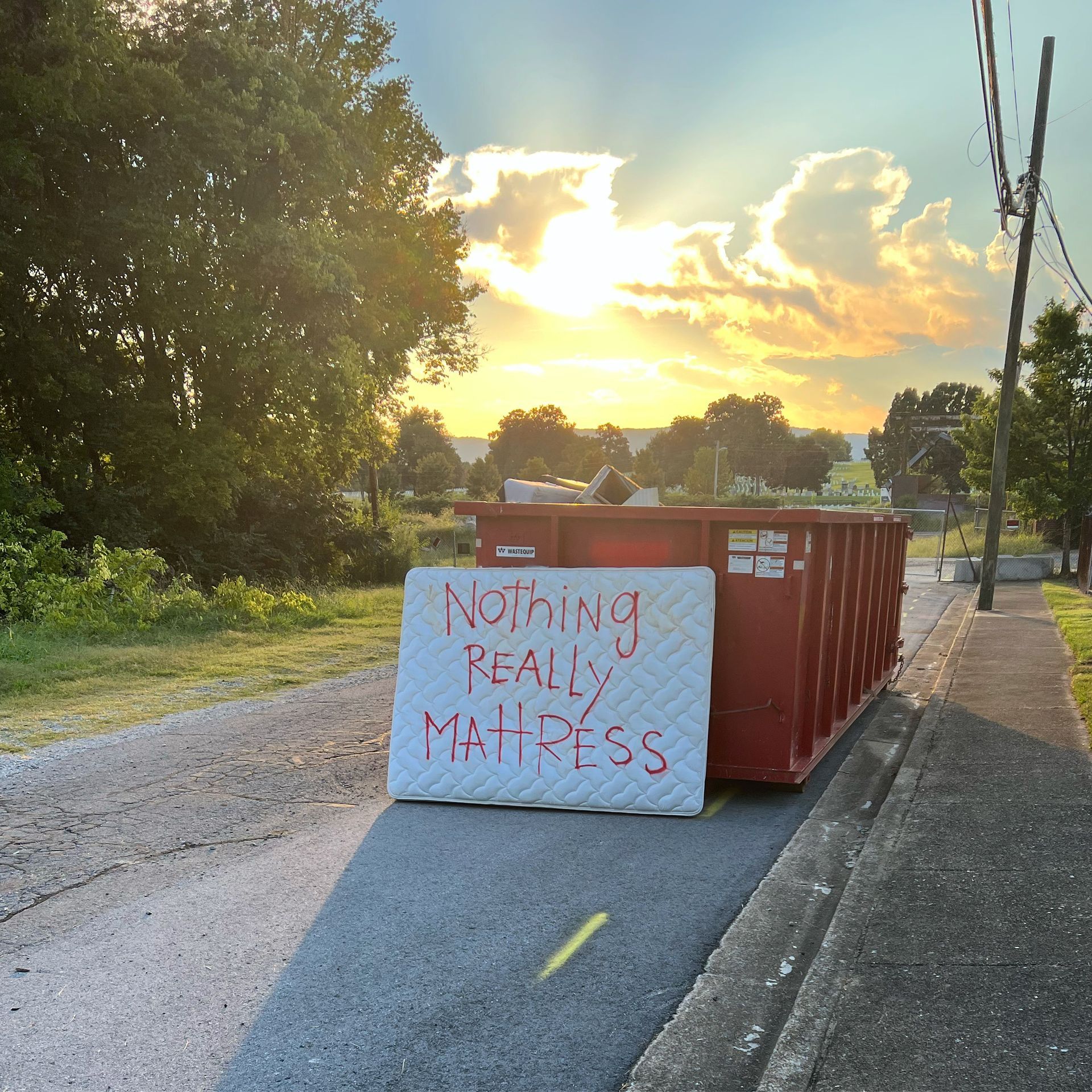 A dumpster with a sign that says nothing really mattress