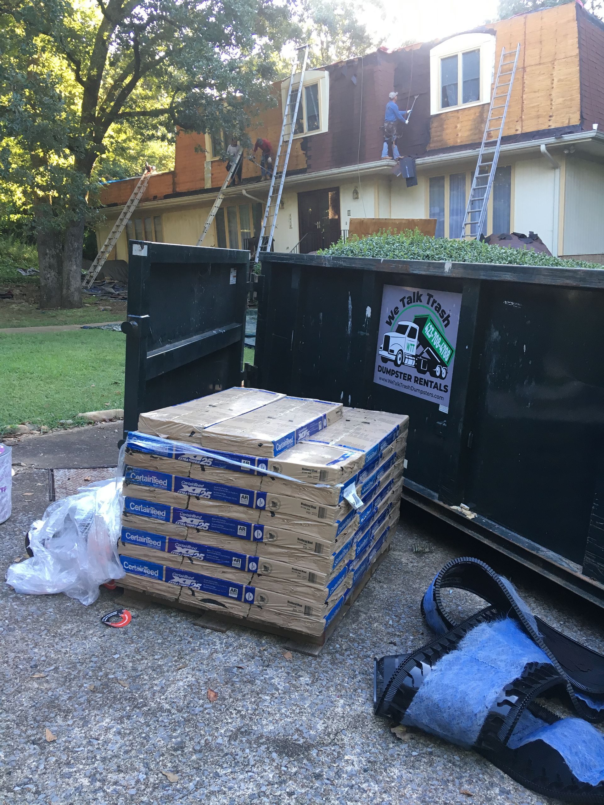 A dumpster is sitting in front of a house that is being remodeled.