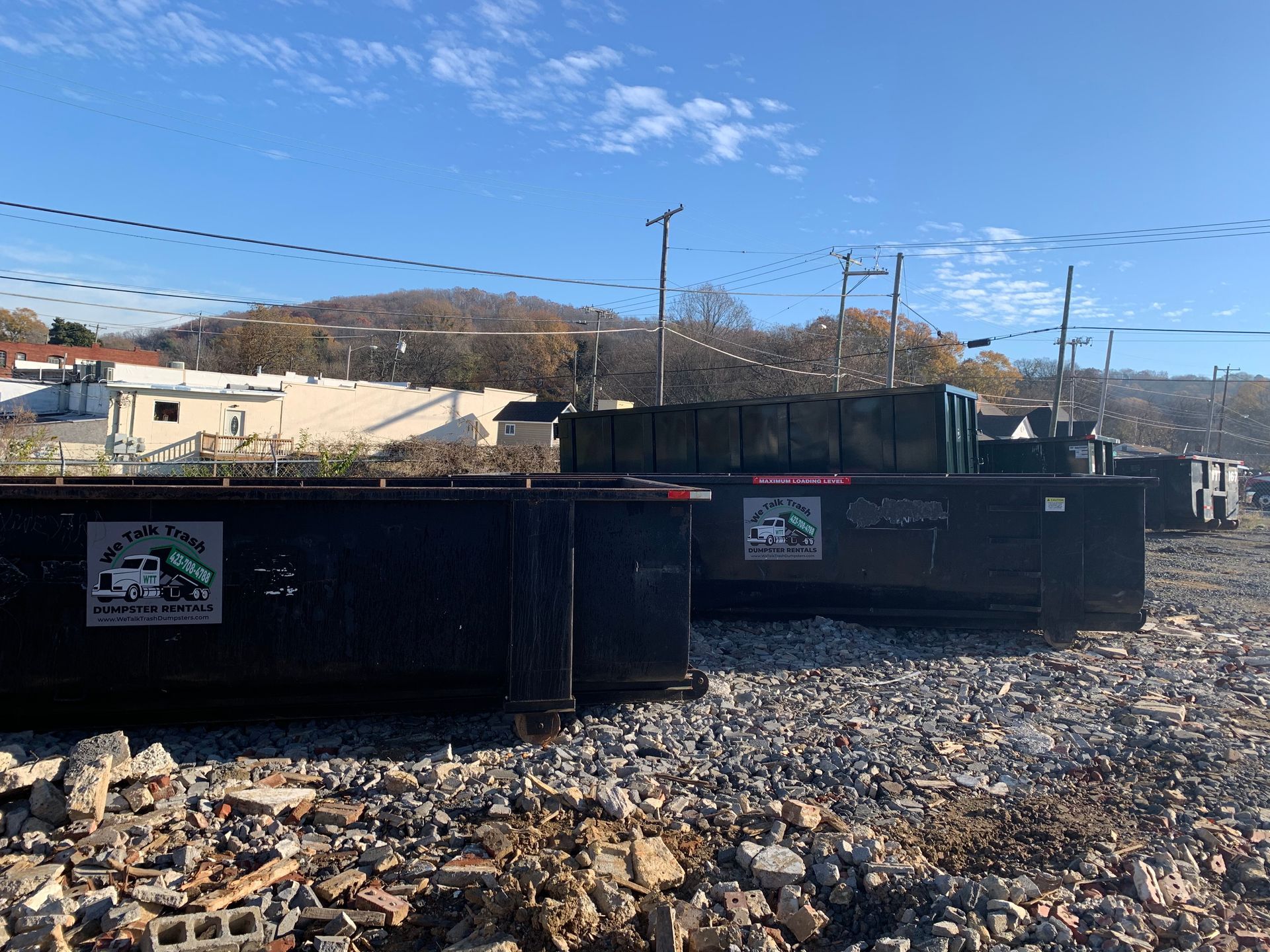 A dumpster is sitting on top of a pile of rocks.