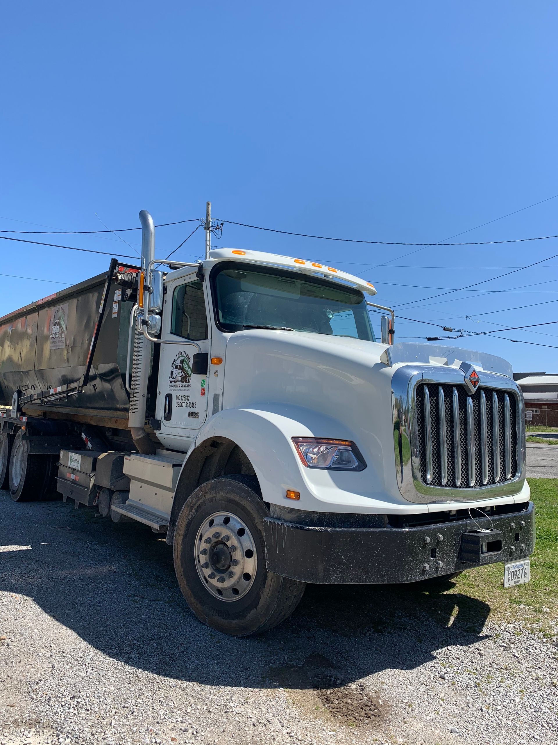 A white dump truck is parked in a gravel lot.