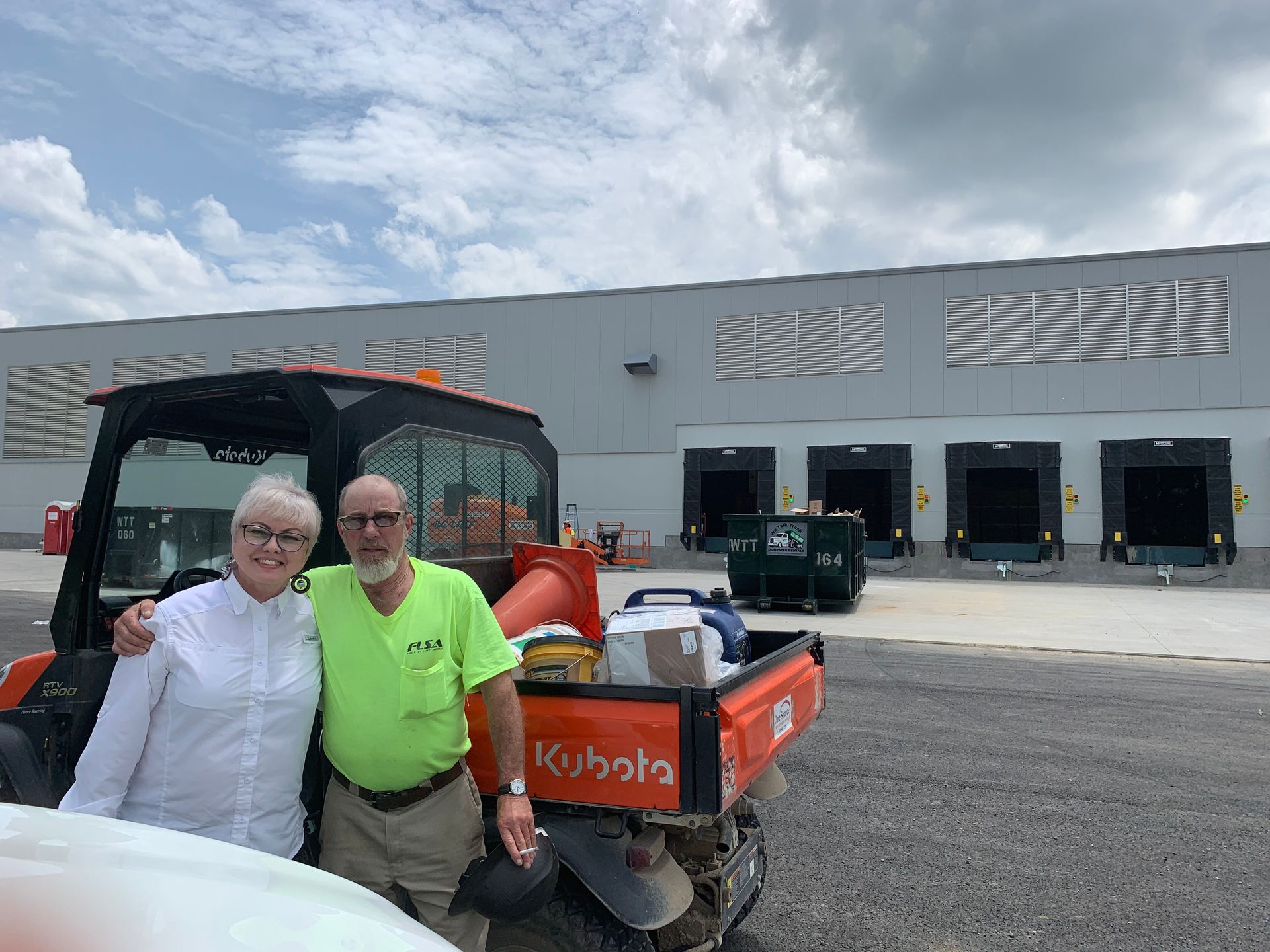 A man and a woman are standing next to a truck in front of a building.