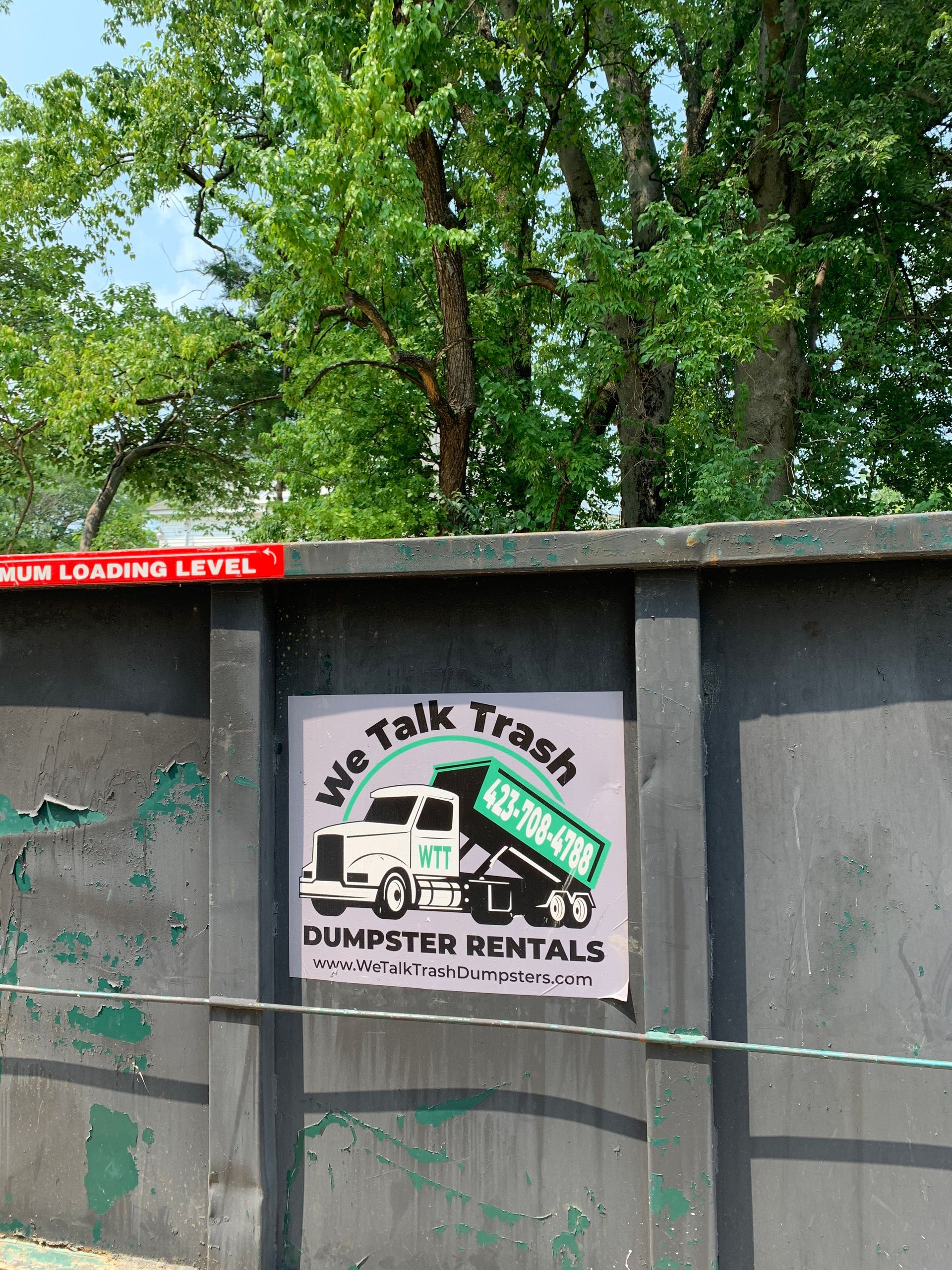 A sign on a wall that says we talk trash dumpster rentals