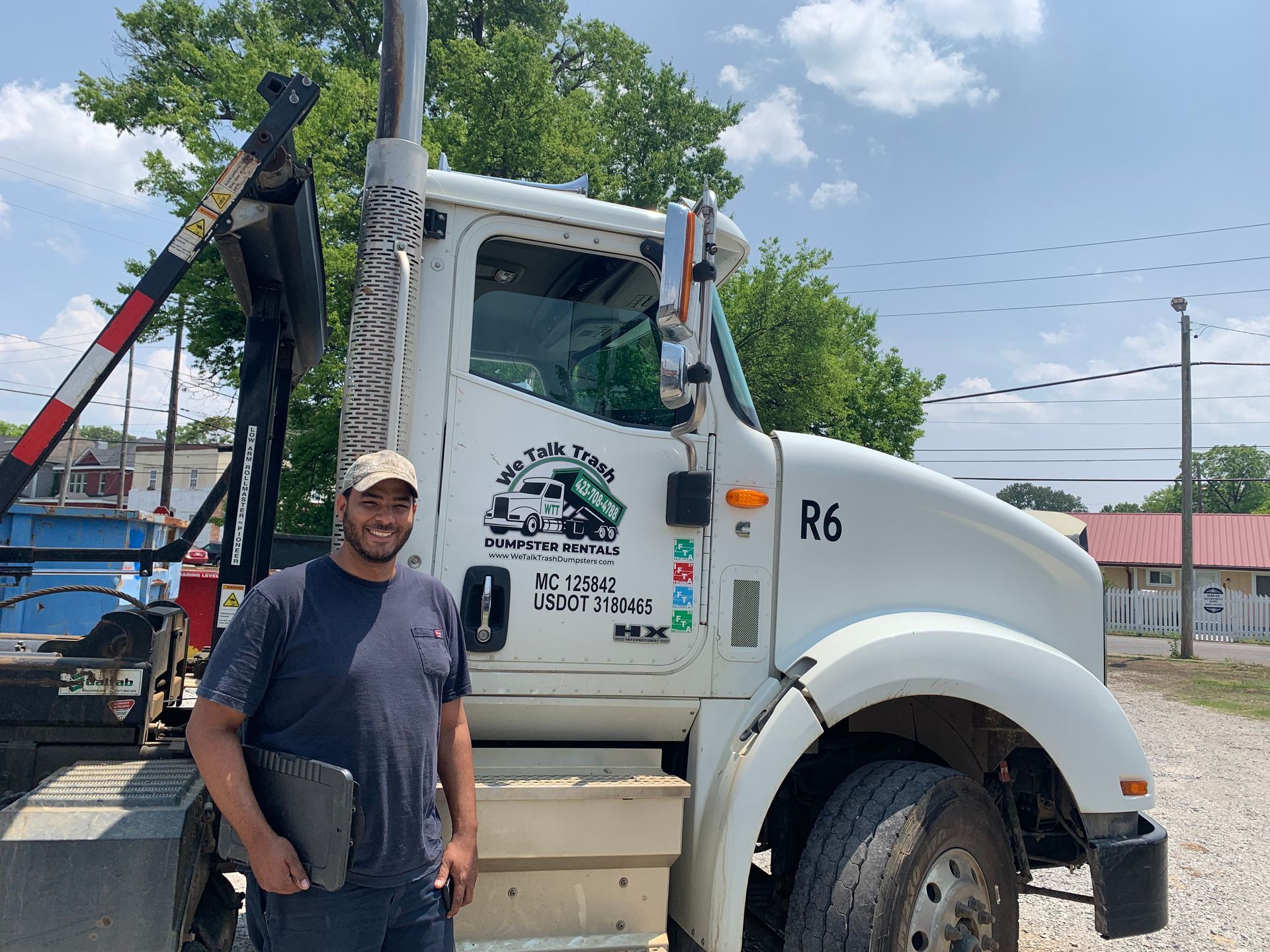A man is standing in front of a white dump truck.