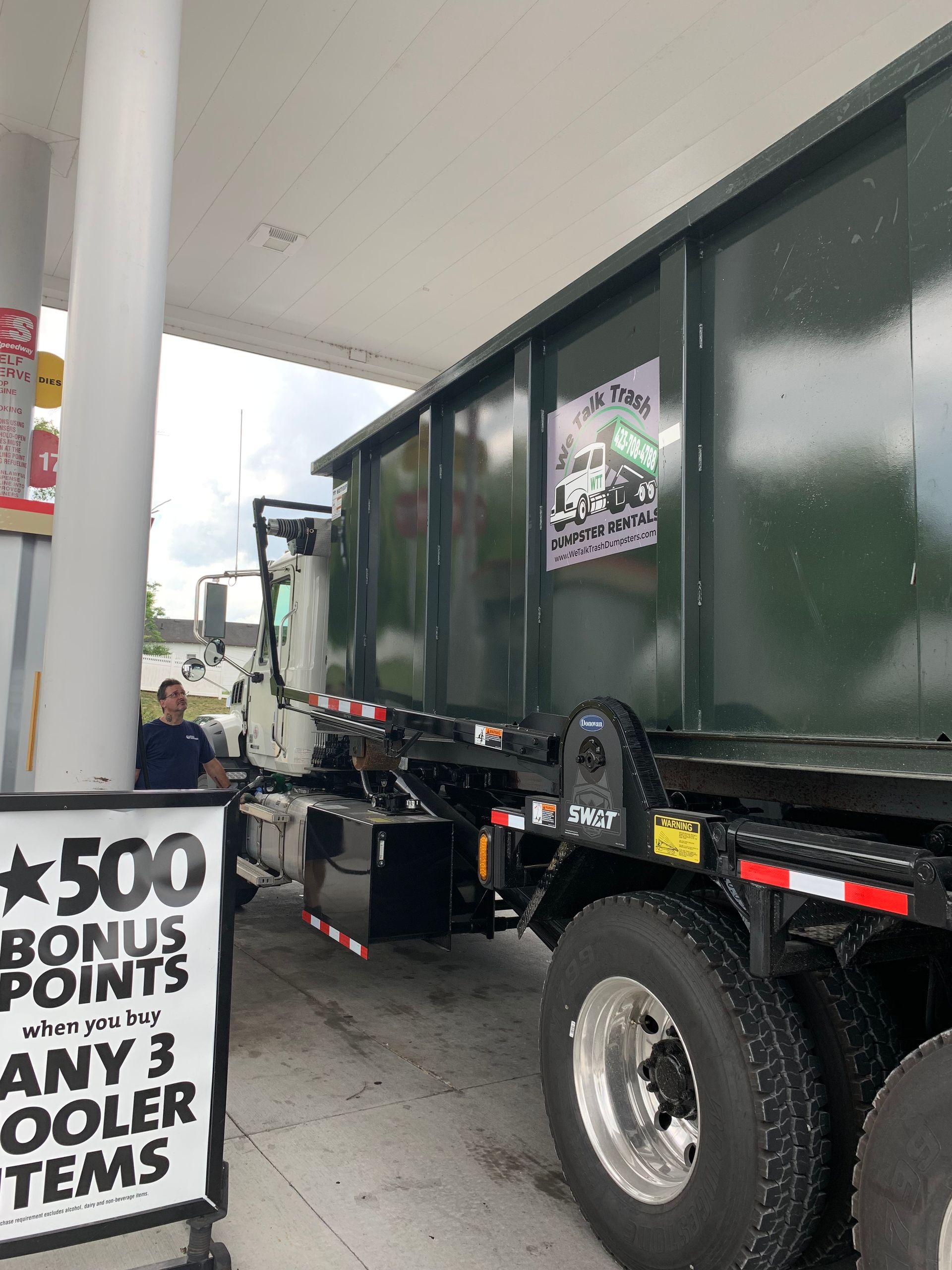 A dump truck is parked in front of a gas station.