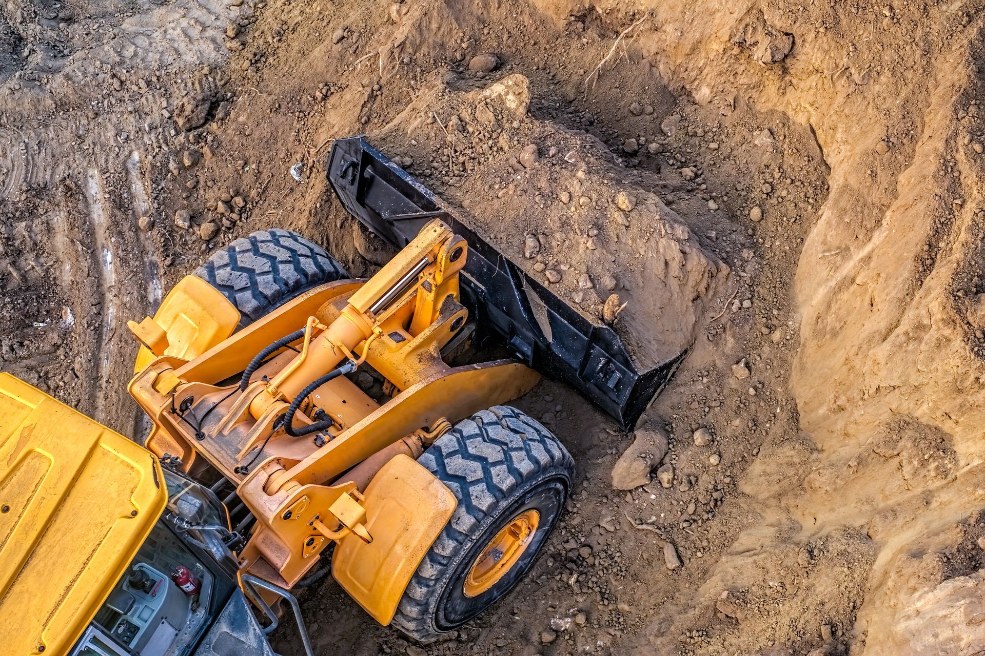 A yellow bulldozer is laying on its side in the dirt.