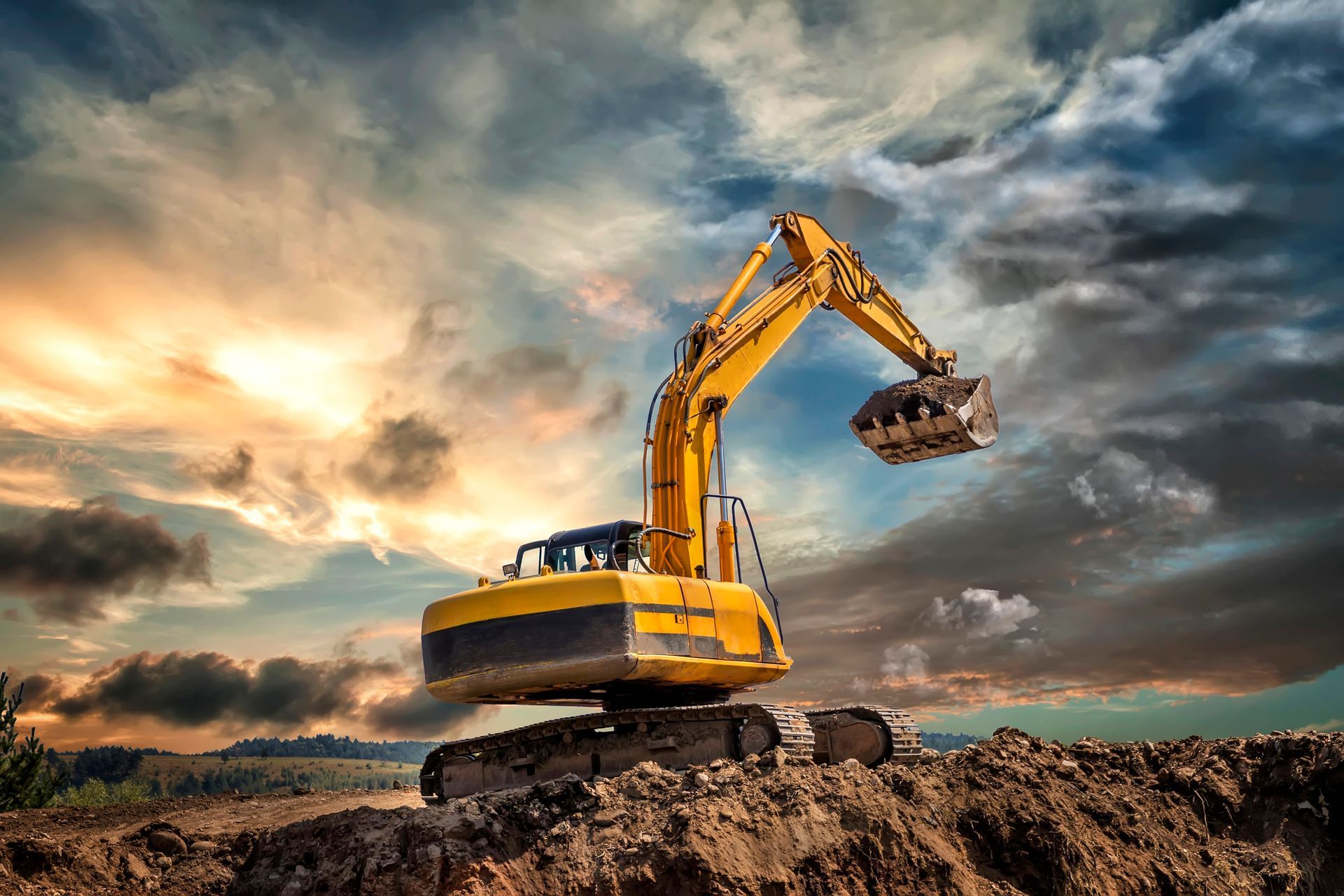 A yellow excavator is sitting on top of a pile of dirt.