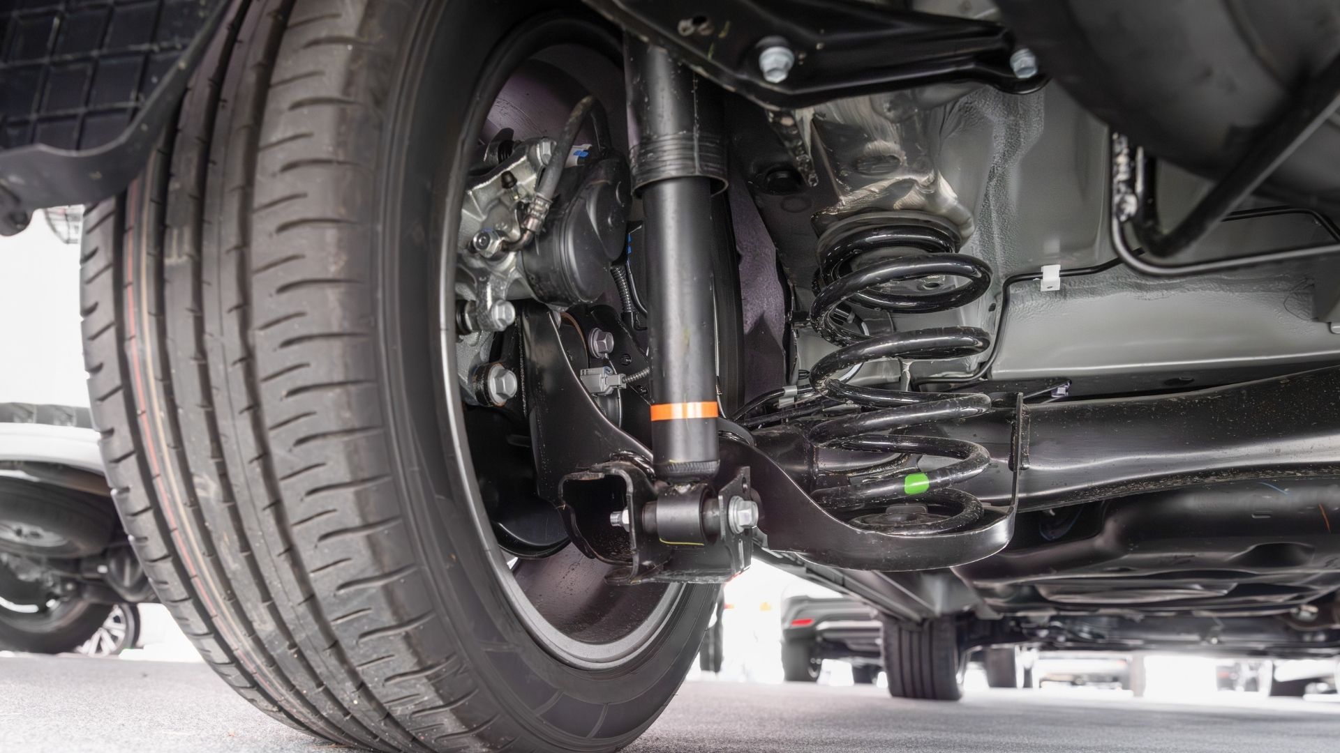 The underside of a car with a shock absorber and a tire.