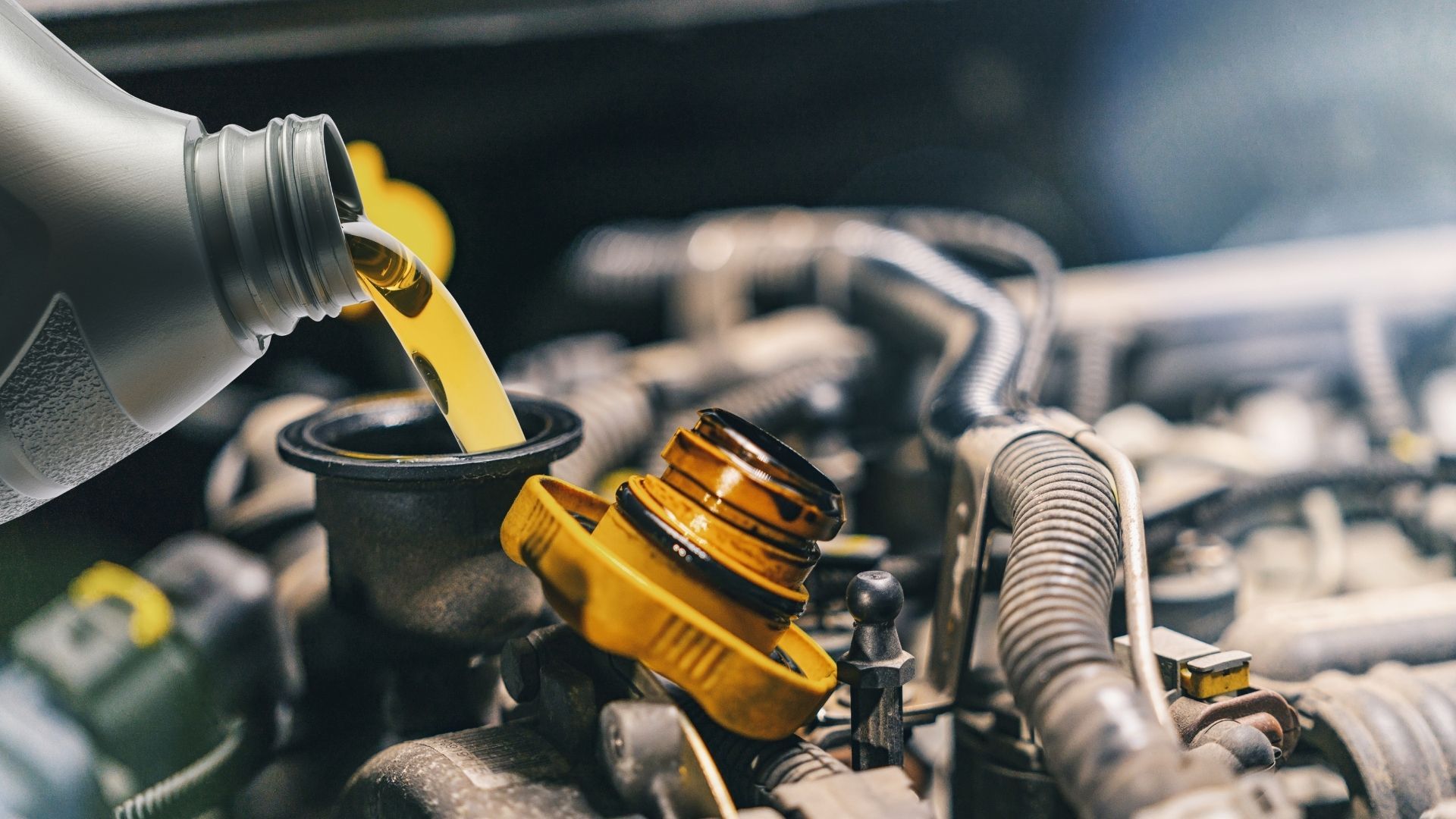 A person is pouring oil into a car engine.