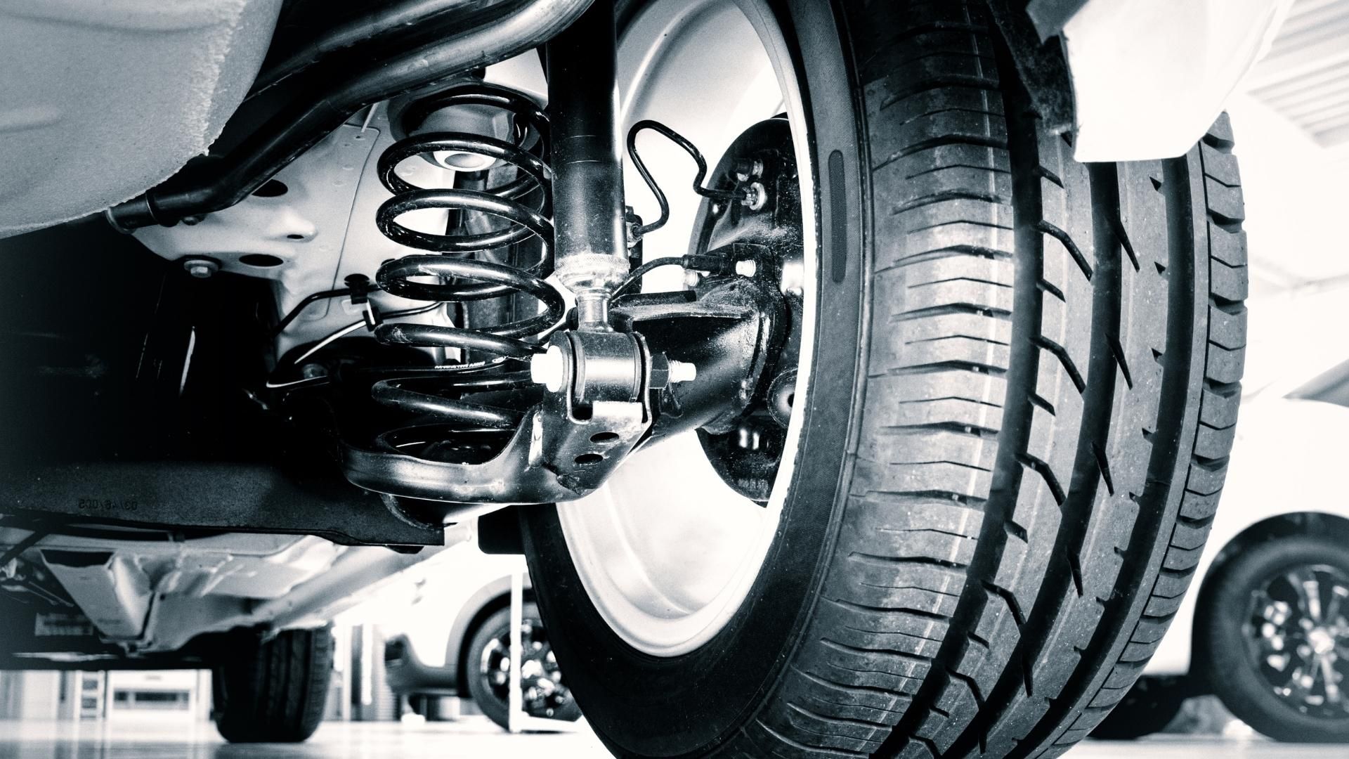 A close up of a car 's suspension and tire in a garage.