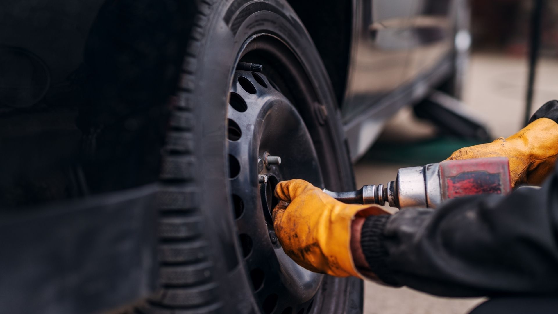 A man is changing a tire on a car with a wrench.