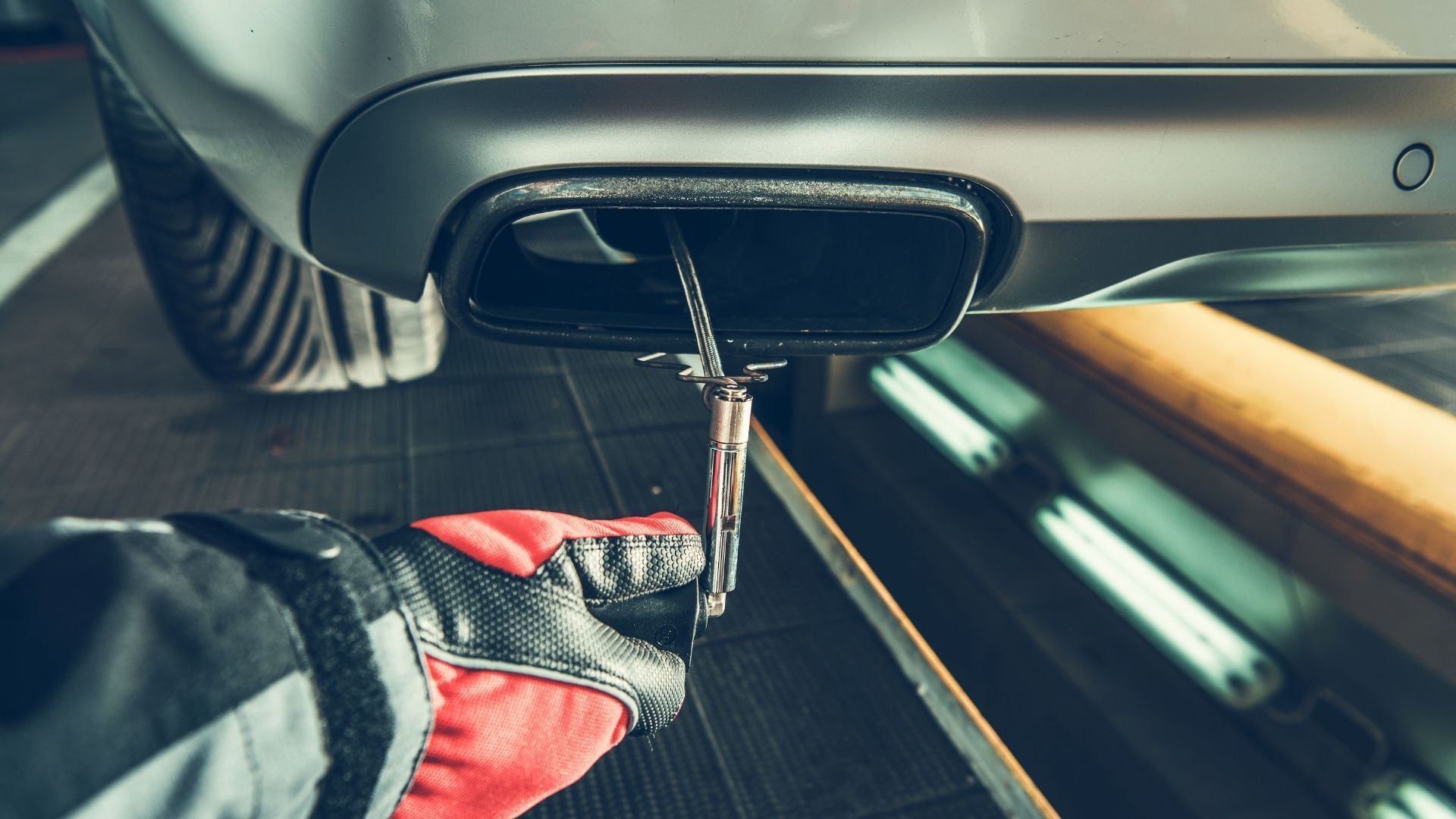 A person is working on the exhaust pipe of a car in a garage.