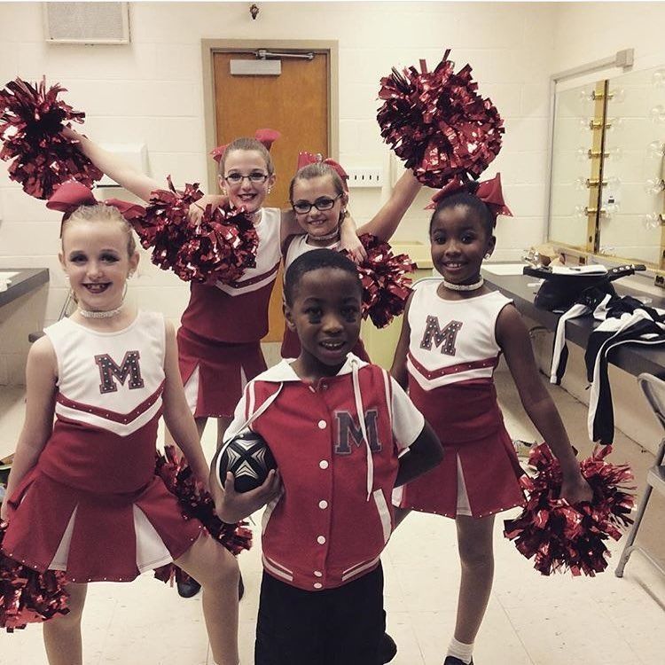 Cheerleaders in red and white uniforms pose with pom-poms in a hallway Cheerleaders in red and white uniforms pose with pom-poms in a hallway