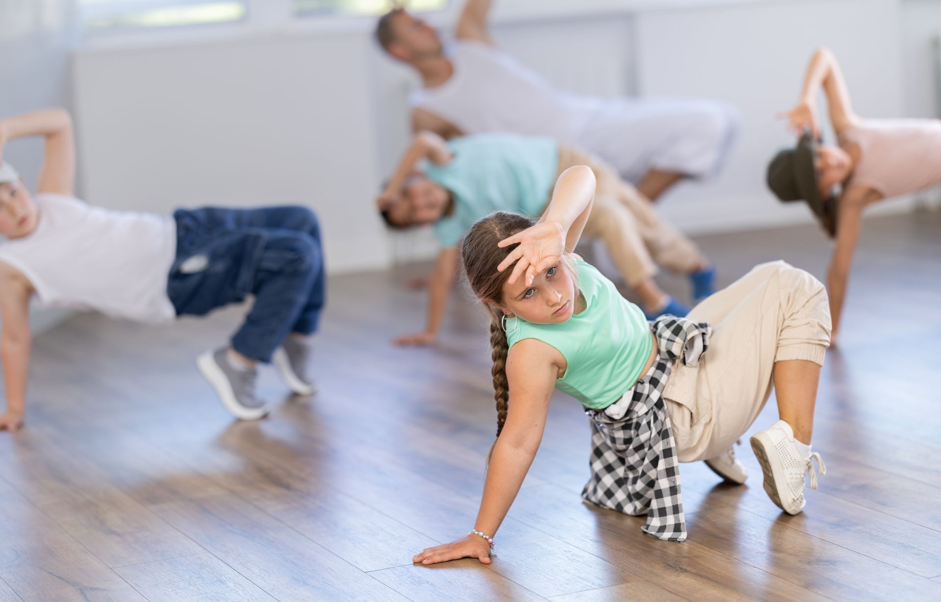 People dancing in a bright studio, with one in a mint green top posing in the foreground. People dancing in a bright studio, with one in a mint green top posing in the foreground.