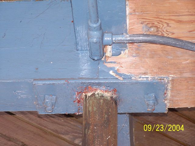 Close-up of a blue-painted metal beam and post joint with a hose or cable attached.