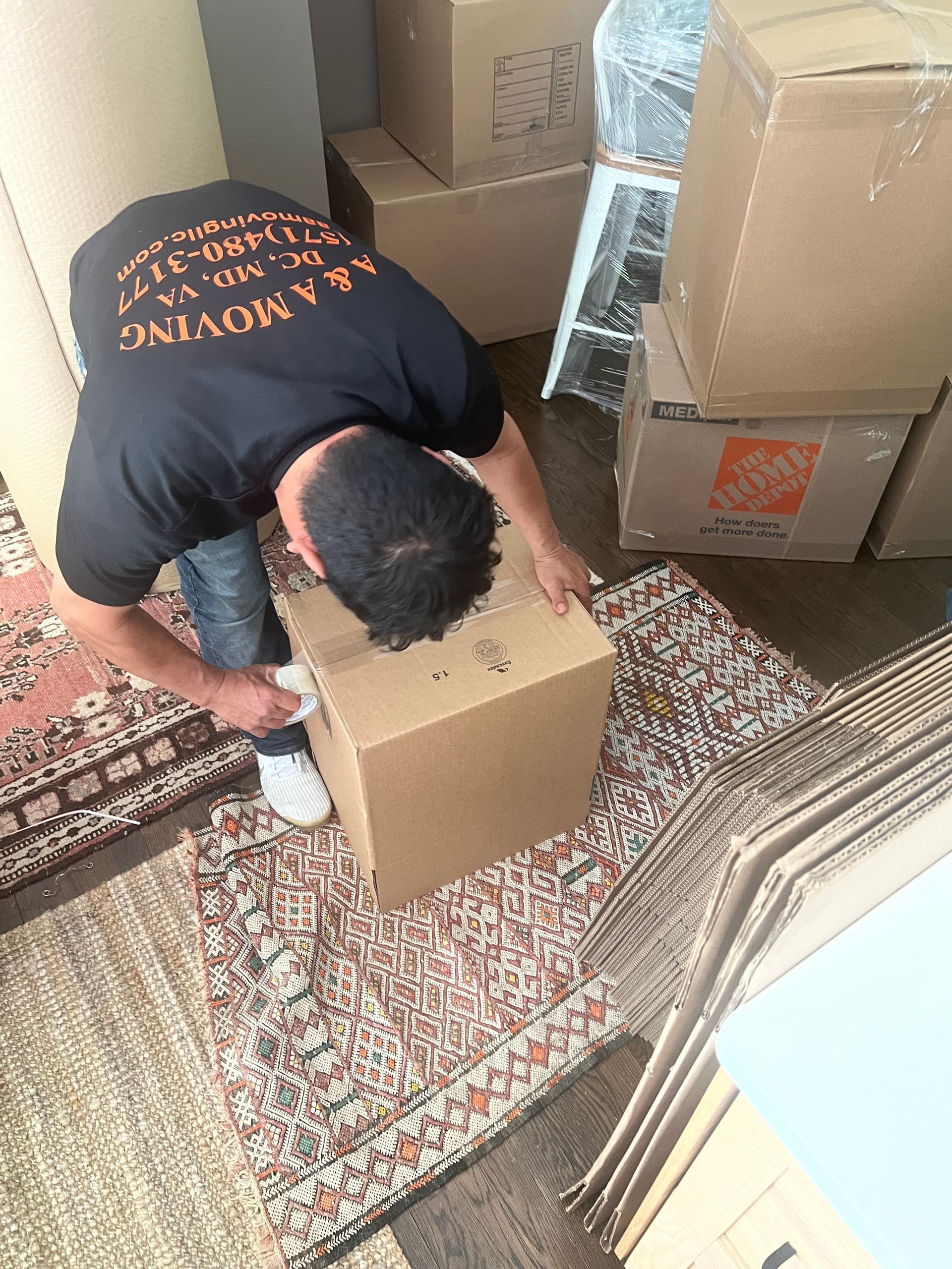 A man is kneeling down next to a cardboard box.