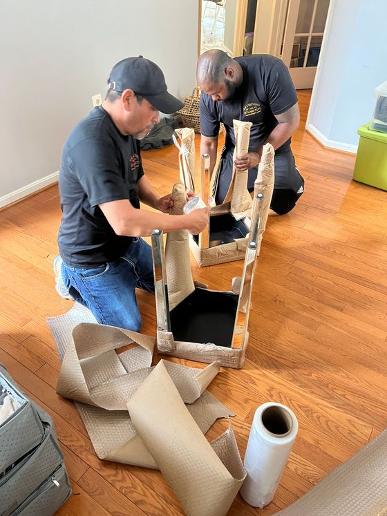 Two men are working on a chair in a living room.