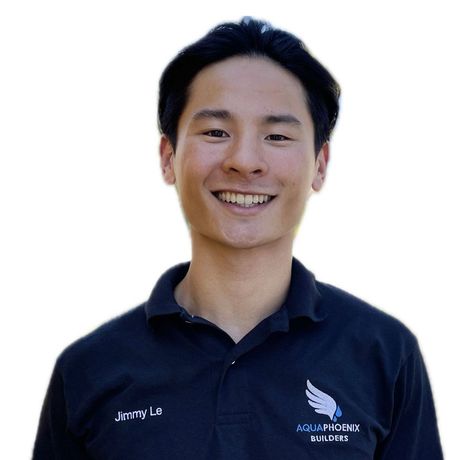 Jimmy Le smiling at the camera, wearing a dark polo shirt with the AquaPhoenix Builders logo.