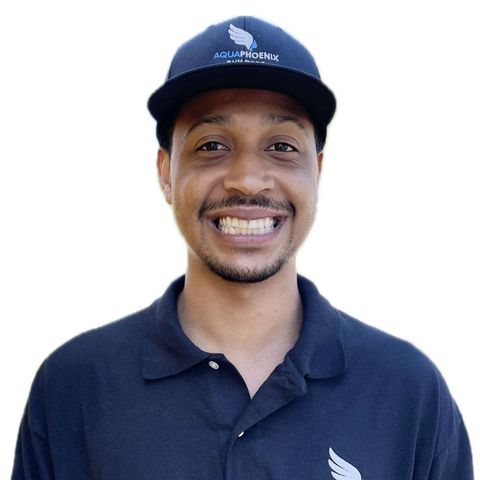 Smiling Black man wearing a black polo shirt and cap, logo on the cap.