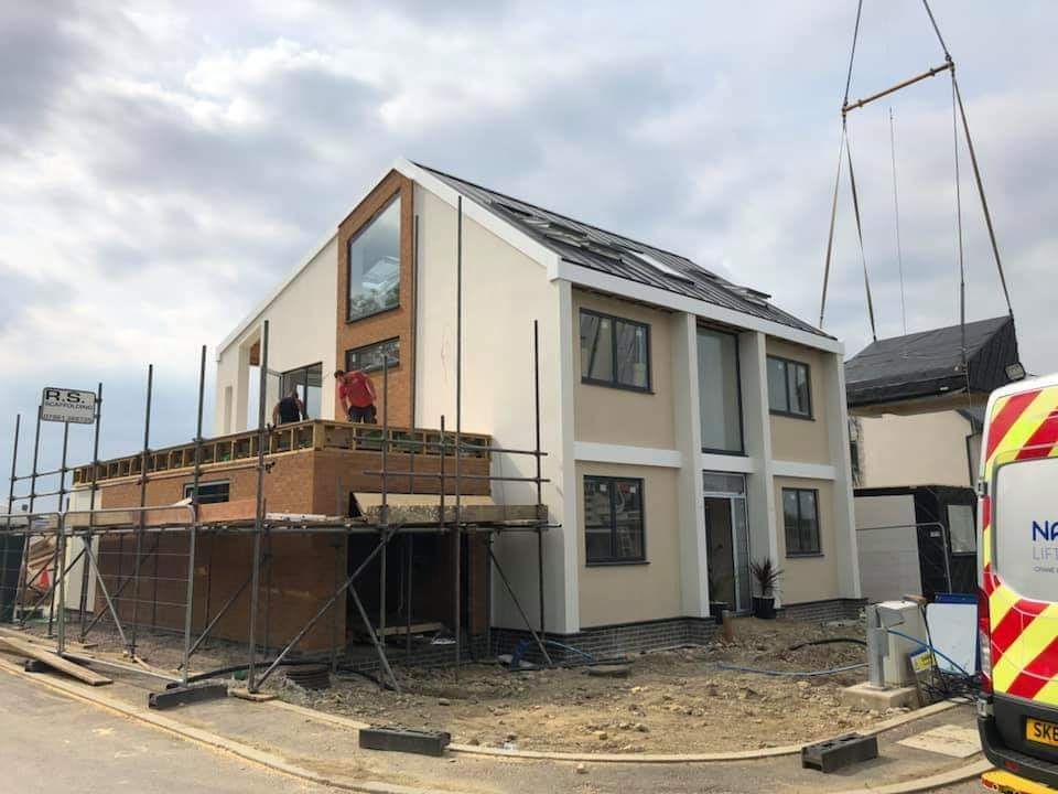 A house is being built with scaffolding and a crane.