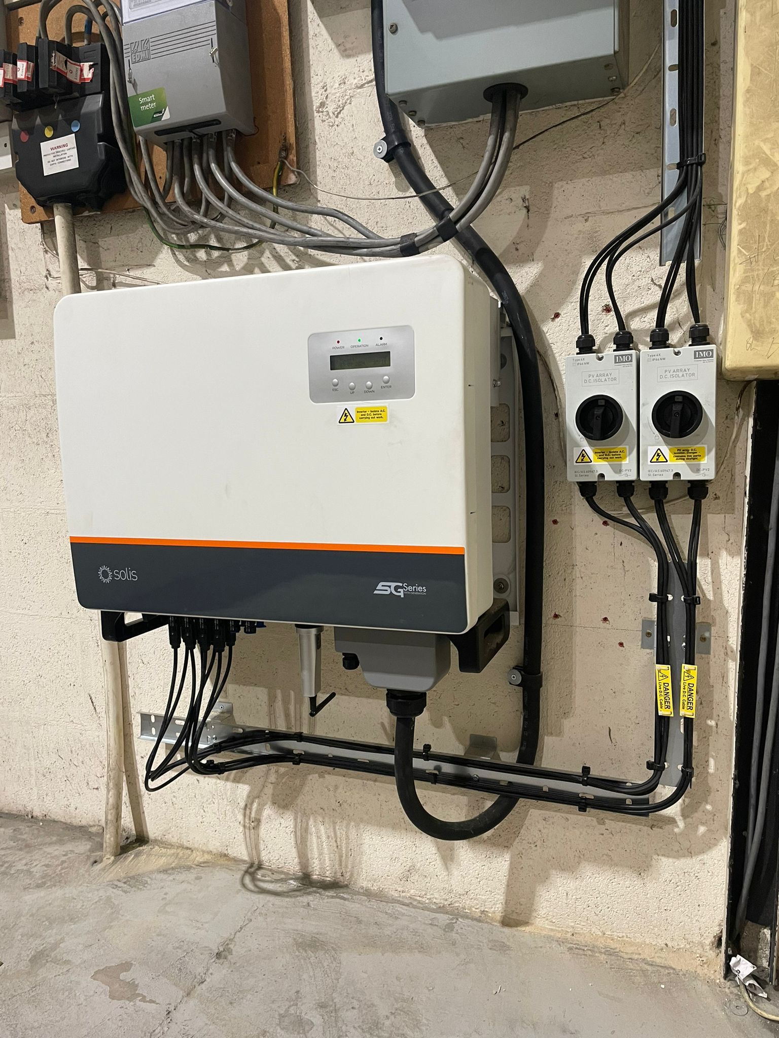 A solar panel inverter is mounted on the side of a building.